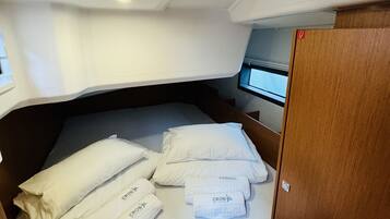 Une petite cabine comprenant un lit, une petite table et une porte en bois.