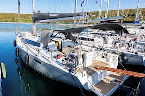 Een zeilboot afgemeerd in een jachthaven, met een kajuit, dek en diverse scheepvaartattributen.