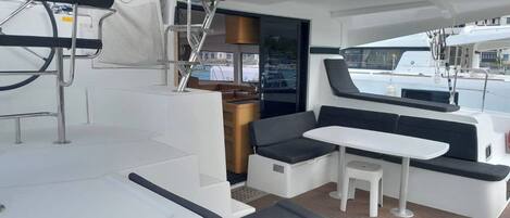 A yacht interior with a dining area, seating, and a view of the marina.