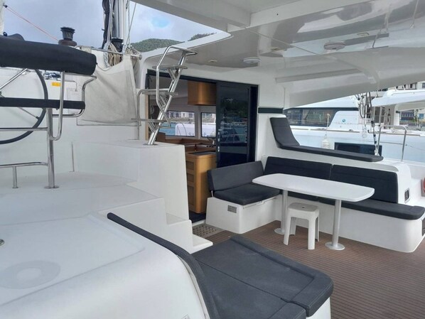 A yacht interior with a dining area, seating, and a view of the marina.