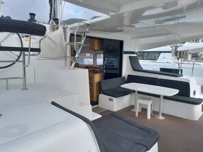 A yacht interior with a dining area, seating, and a view of the marina.