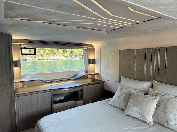 A modern interior with a bed, a desk, and a window overlooking water.