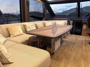 Un intérieur moderne avec un canapé, une table et une vue sur la mer, grâce à de grandes fenêtres.