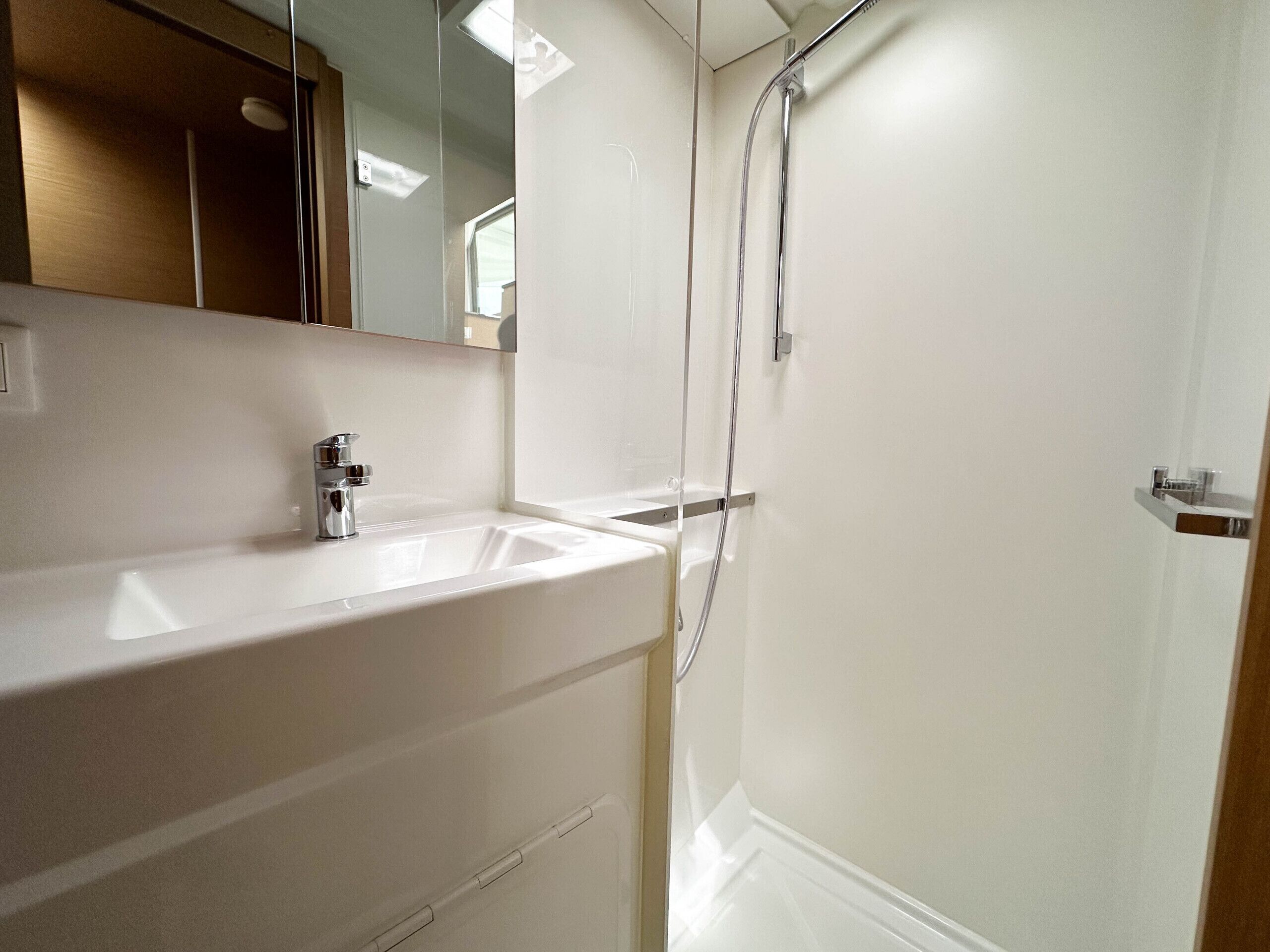 Een moderne badkamer met een grote witte wastafel, een spiegel en een douchecabine.