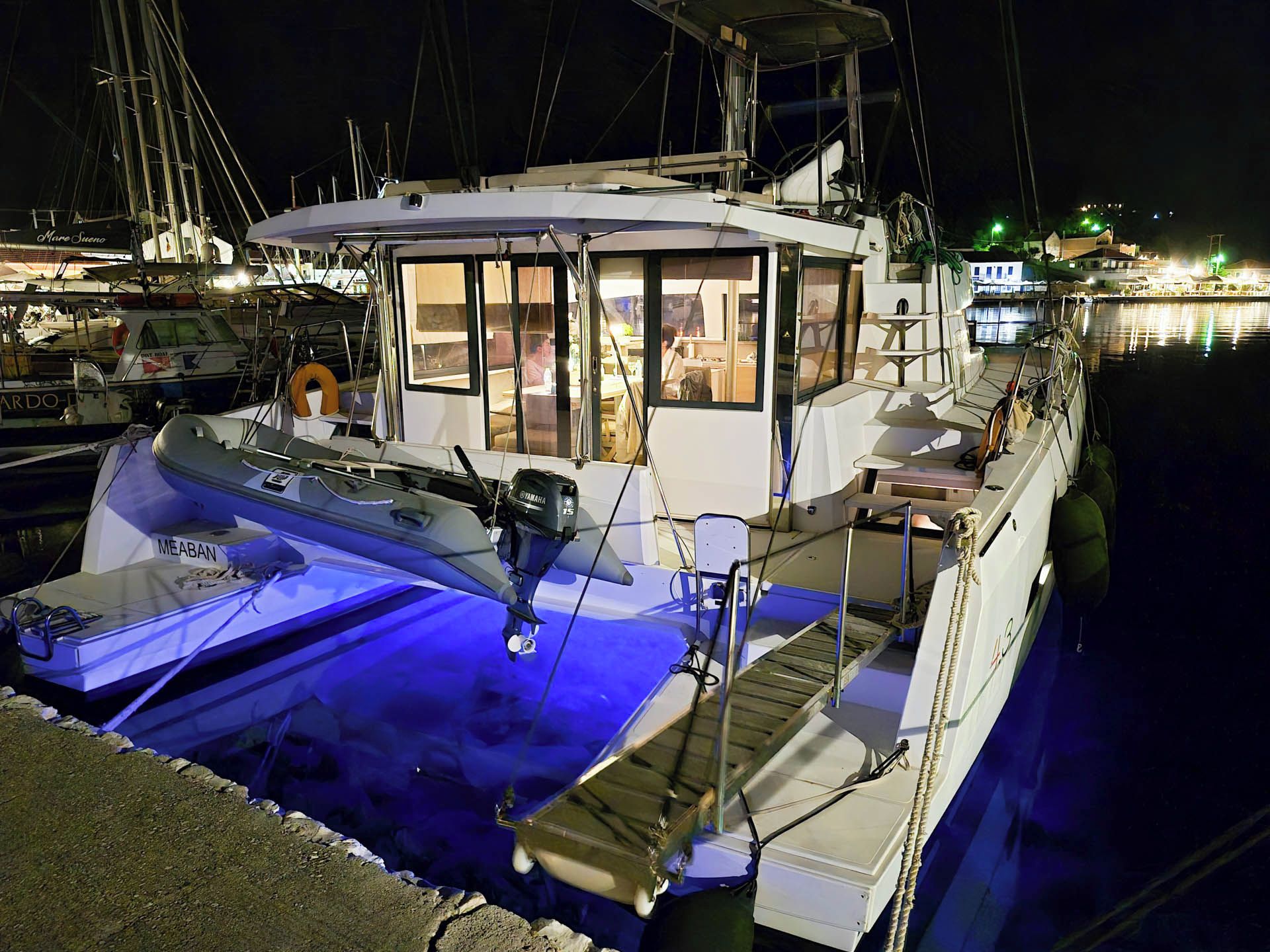 Un barco atracado en un puerto deportivo con una cubierta techada, camarote con ventanas y un motor fueraborda Yamaha visible.