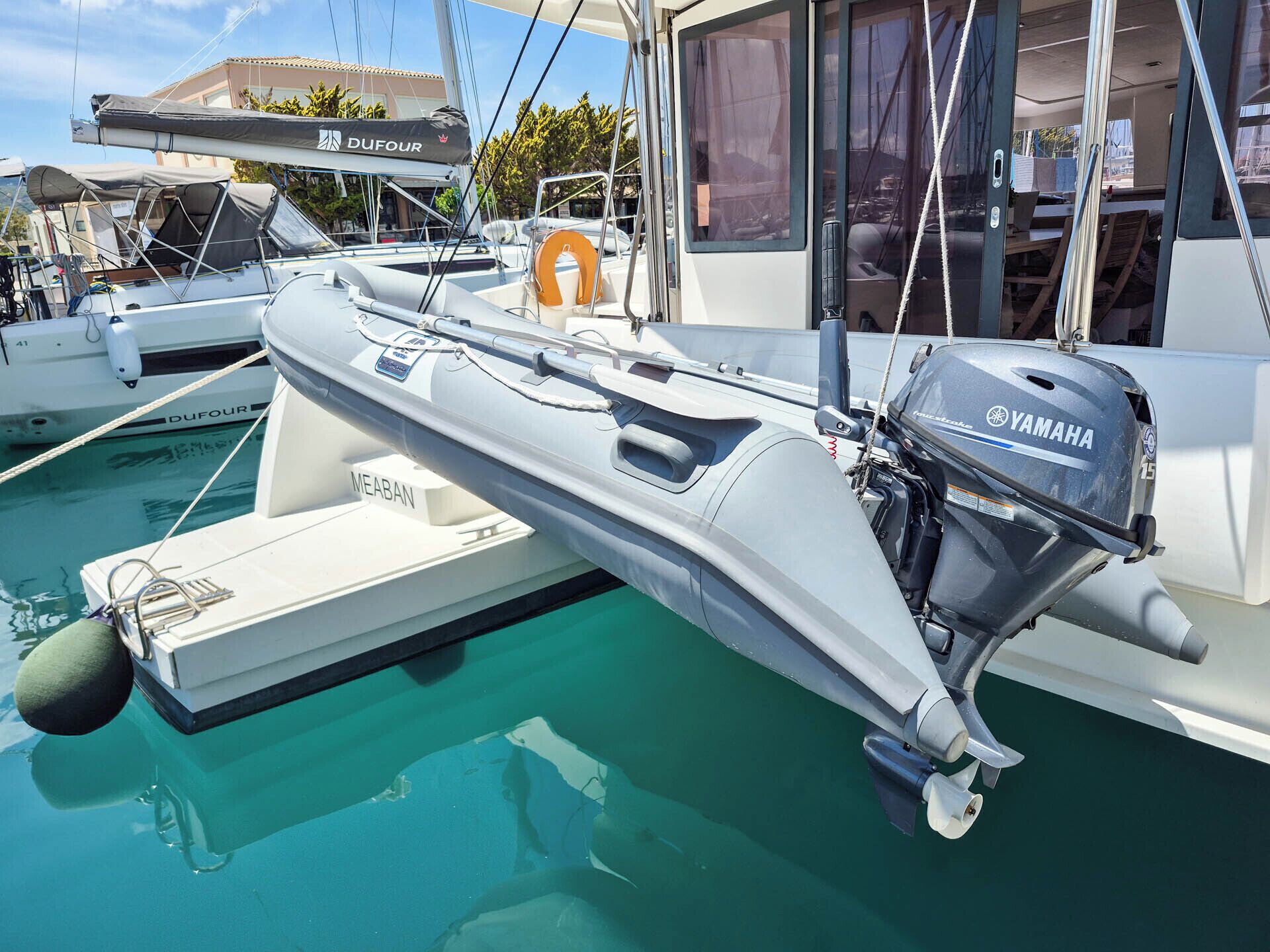 Un yacht équipé d’un moteur hors-bord Yamaha, portant une plaque signalétique avec l’inscription « MEABAN » et arborant le logo « DUFOUR » sur la cabine.