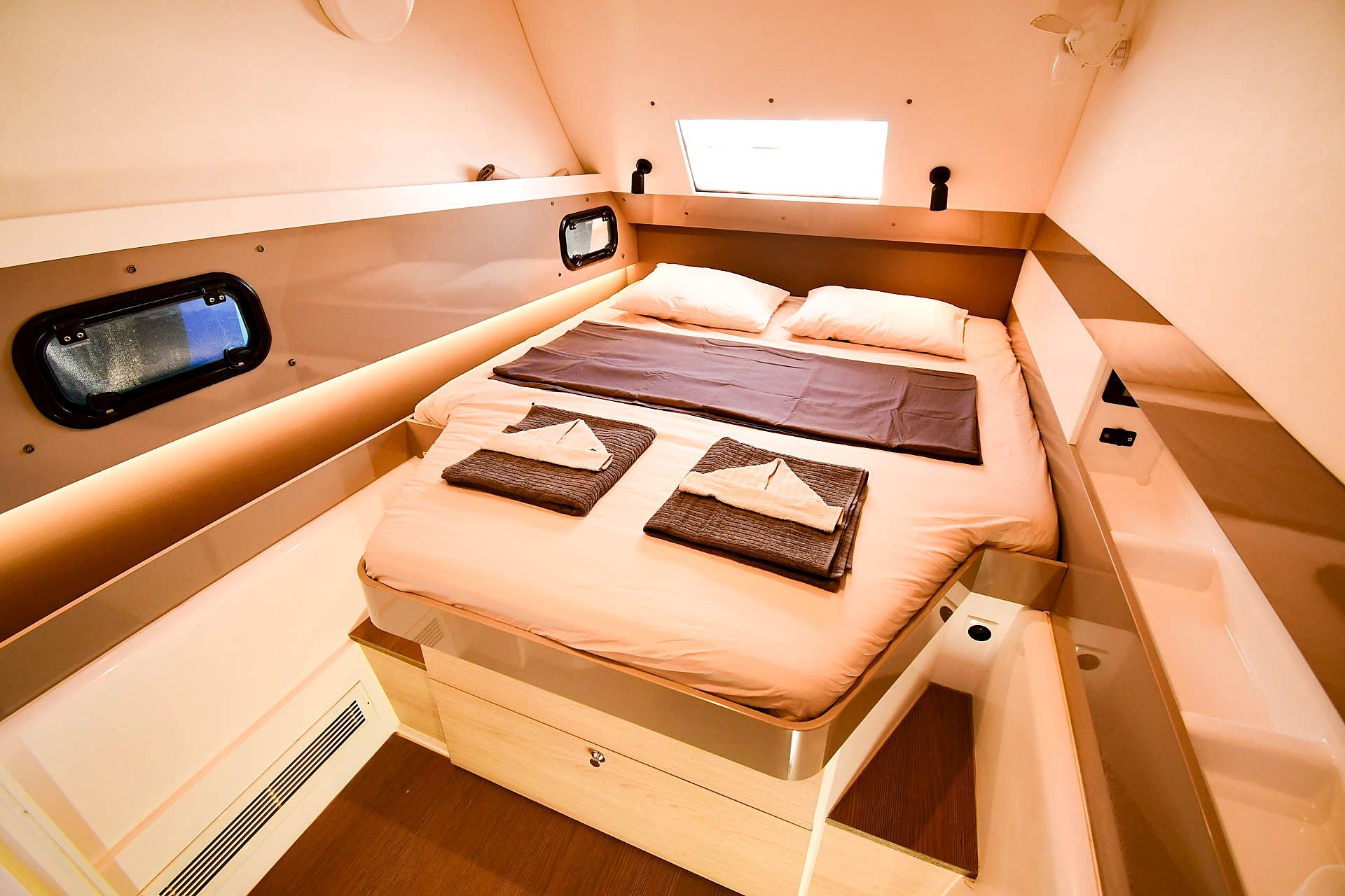 A compact, well-lit room with a bed, a small window, and a control panel.