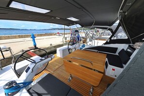 A boat deck with a steering wheel, wooden table, and seating area. - Sun-Kissed Sailing Adventure in Zadar, Croatia (Biograd na moru)