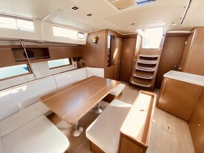 A compact kitchen area with a wooden table, white bench seating, and built-in storage cabinets. - Sun-Kissed Sailing Adventure in the Ionian Islands, Lefkada (Lefkada)