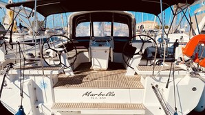 En båd ved navn 'Marbella' med dæk af træ, rat og forskelligt navigationsudstyr.