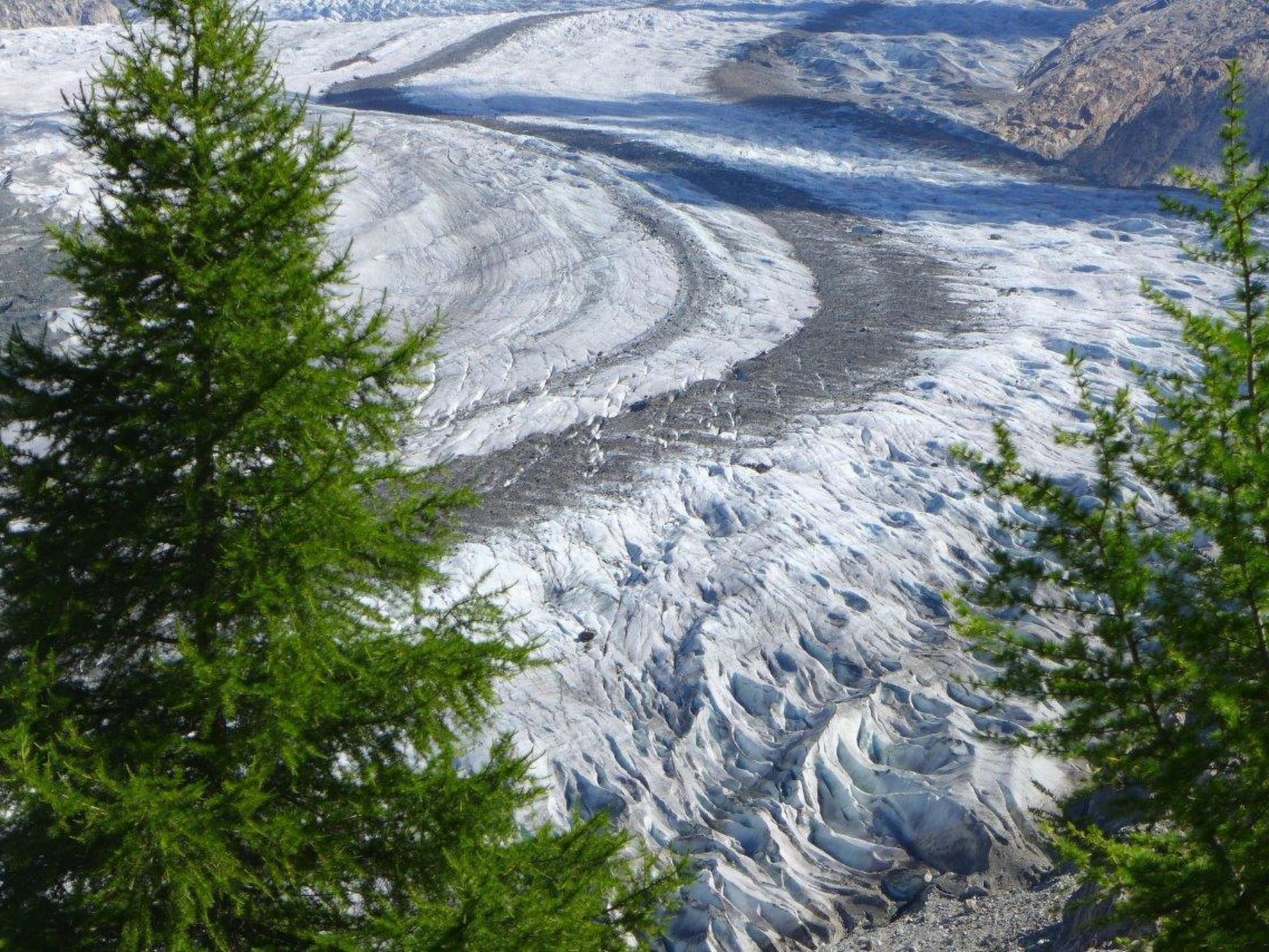 Un glaciar con un río serpenteante, rodeado de terreno rocoso y vegetación escasa.