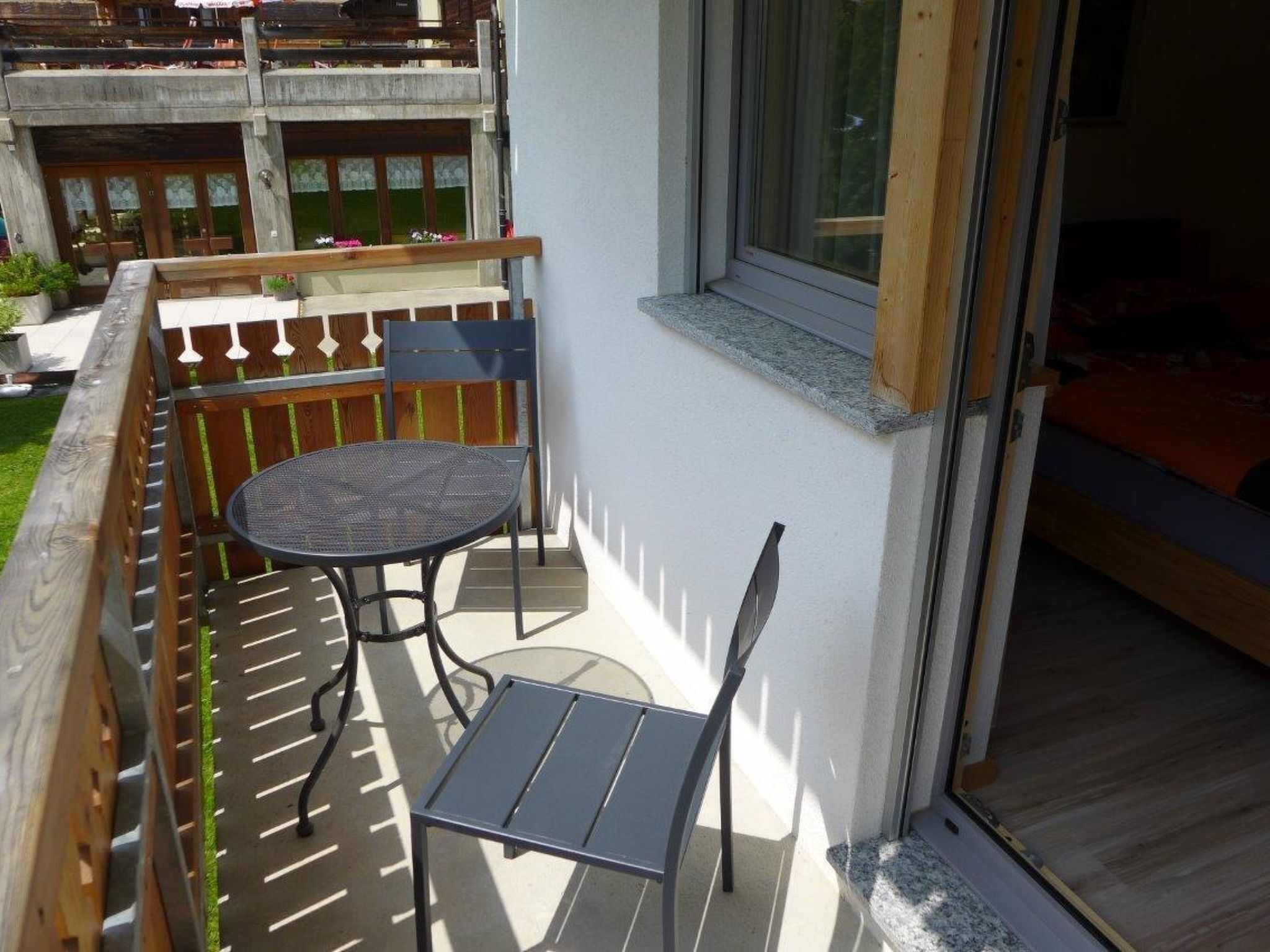 Ein Balkon mit Tisch und Stühlen, einem Holzzaun und einem Fenster.