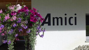 Seinässä on sana «Amici», ja sen edessä roikkuu kukkakimppu.