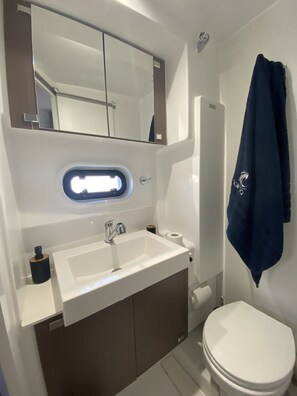 A modern bathroom with a white sink, mirror, and toilet. - Sun-Kissed Sailing Adventure in the Ionian Islands (Kontokali)