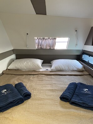 A bedroom with a bed, pillows, a window with curtains, and two towels on the bed. - Sun-Kissed Sailing Adventure in the Ionian Islands (Kontokali)
