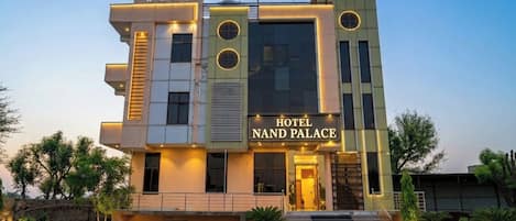A modern hotel building with a sign reading 'HOTEL NAND PALACE.'