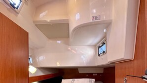 Un espacio interior compacto y bien iluminado, con una cama litera, una pequeña zona de estar y un panel de control.