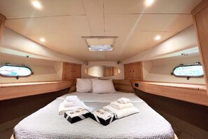 A cabin with a bed, two windows, a mirror, and a ceiling light. - Sun-Kissed Sailing Adventure in Islas Sarónicas (Piraeus)