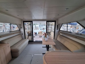 A boat interior with a central table, seating on both sides, and a view of the marina outside. - Sun-Kissed Sailing Adventure in Islas Sarónicas (Piraeus)