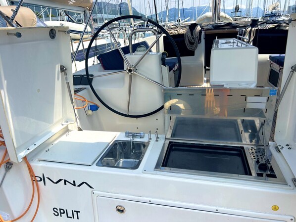 A boat's interior with a steering wheel, a sink, and the name 'SPLIT' on the side. - Sun-Kissed Sailing Adventure in Split, Croatia (Kaštel Gomilica)