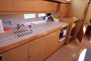 A compact kitchen with wooden cabinets, a sink, and a countertop. - Sun-Kissed Sailing Adventure in Split, Croatia (Kaštel Gomilica)