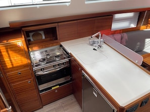 A compact kitchen with wooden cabinetry, a stainless steel stove, and a sink. - Sun-Kissed Sailing Adventure in Istria, Croatia (Pula)