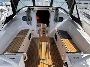 A boat deck with a central aisle, seating areas on either side, and a small enclosed space at the back. - Sun-Kissed Sailing Adventure in Istria, Croatia (Pula)
