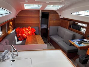 A compact interior with a sofa, a small table, a bunk bed, and a skylight. - Sun-Kissed Sailing Adventure in Istria, Croatia (Pula)