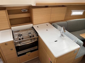 A compact kitchenette with a stove, oven, sink, and wooden cabinetry. - Sun-Kissed Sailing Adventure in Istria, Croatia (Pula)