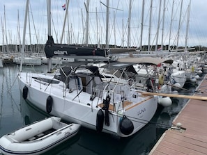 A marina with multiple sailboats docked, a smaller boat in the foreground, and a wooden dock. - Sun-Kissed Sailing Adventure in Istria, Croatia (Pula)