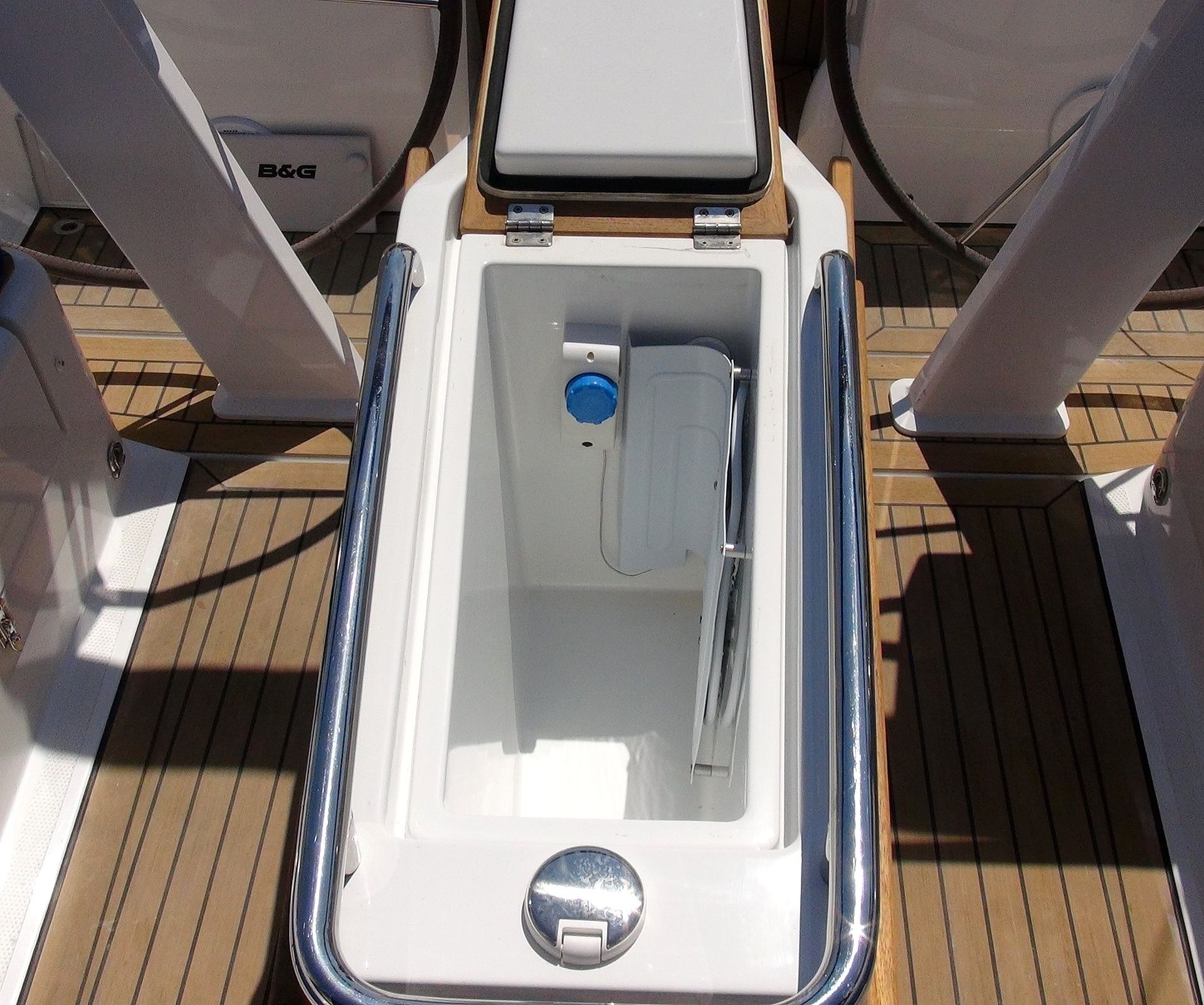 A boat's interior with a white storage compartment, a blue handle, and a metal latch.