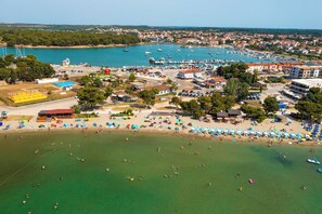 An aerial view of a coastal town with a marina, beach, and various buildings.