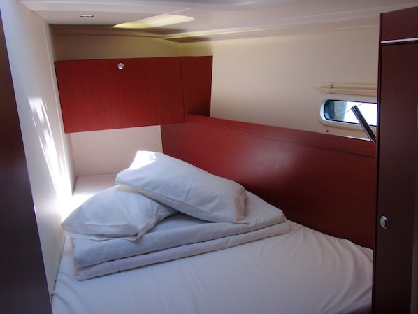 A compact room with a bed, a window, and a red wall.