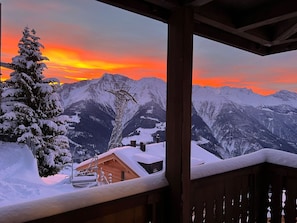 Eine verschneite Berglandschaft mit einer Holzhütte und einem mit Schnee bedeckten Baum.