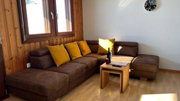 A modern living room with a brown leather sofa, wooden flooring, and a wooden wall.