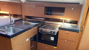 A compact kitchen with a sink, stove, oven, and wooden cabinets. - Sun-Kissed Sailing Adventure in Istria, Croatia (Pula)