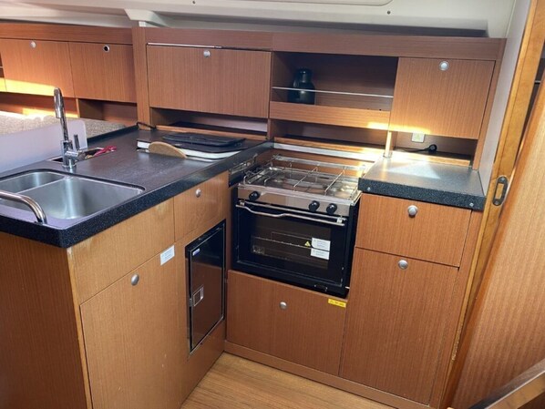 Una cocina compacta con un fregadero, estufa, horno y armarios de madera.