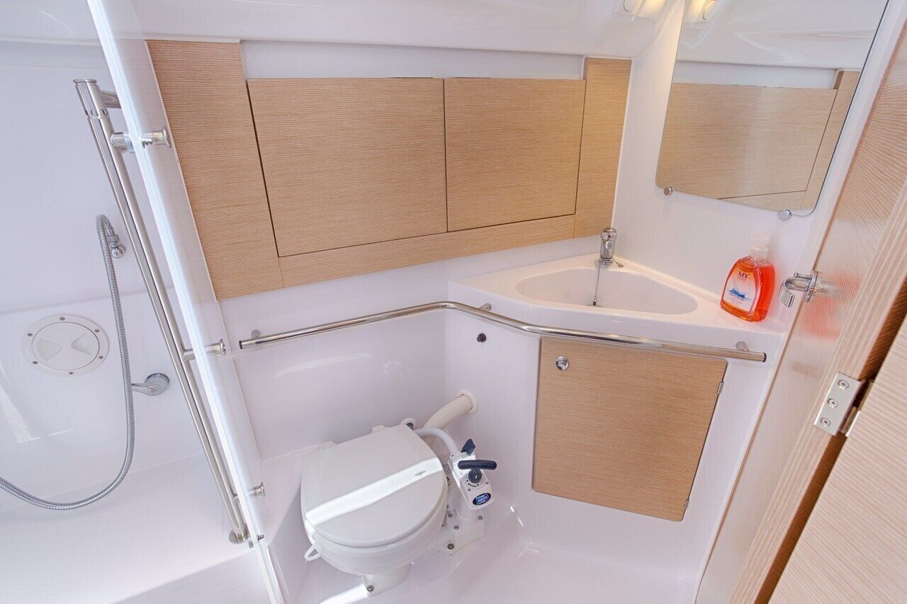 Ein kleines Badezimmer mit Dusche, Toilette und Waschbecken, ausgestattet mit Holzvertäfelung und einem Spiegel.