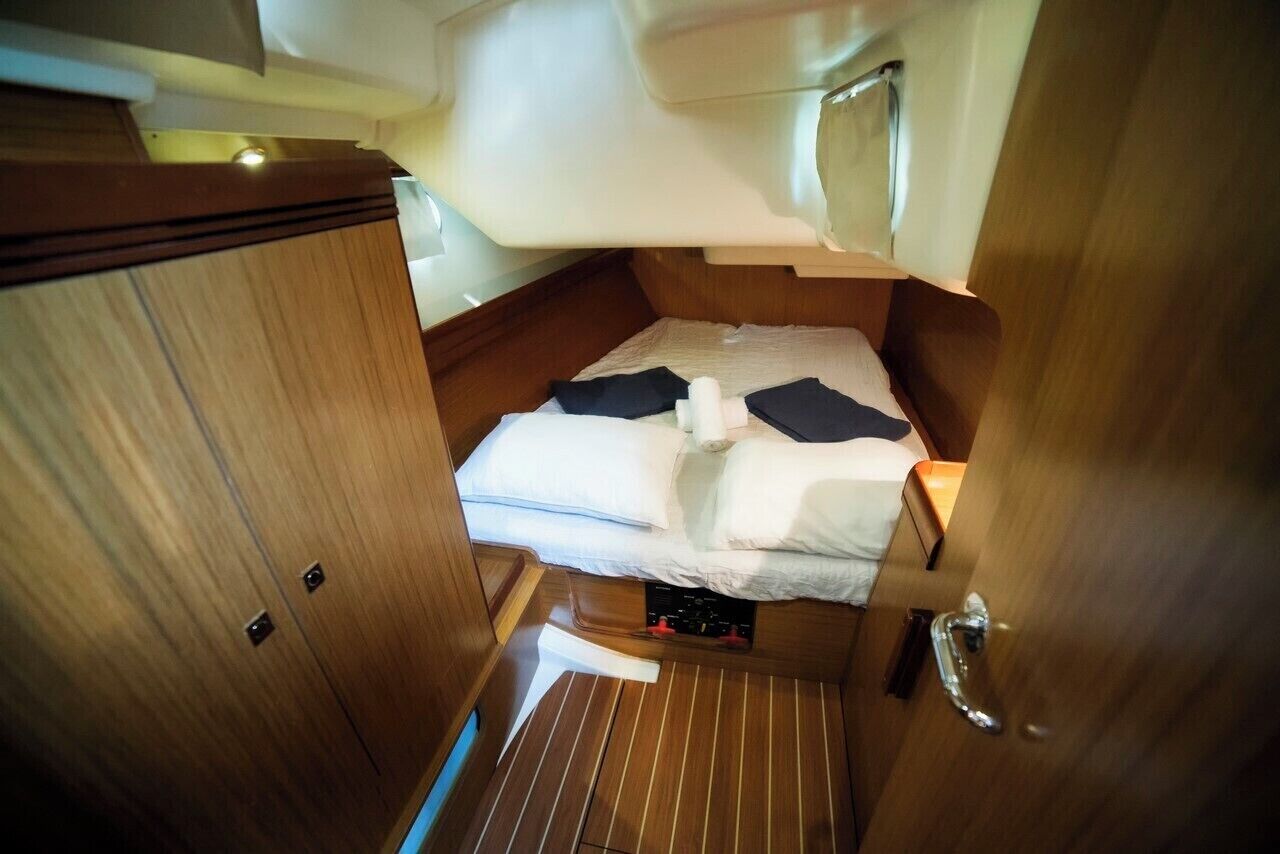 A compact cabin with a bed, a small control panel, and a door.