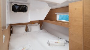 Ein kompakter, gut beleuchteter Raum mit einem Etagenbett, einem kleinen Fenster mit Blick und einer Bedienkonsole über dem Bett.