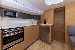 Eine kompakte Küche mit Einbauofen, Mikrowelle und kleinem Kühlschrank.