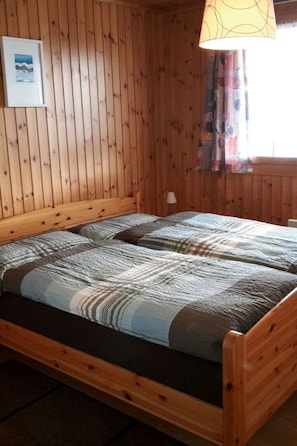 A wooden cabin room with a bed and a lamp.