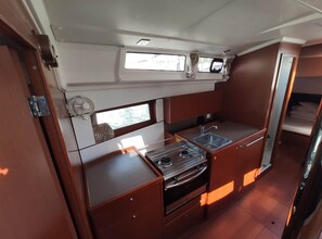 A compact galley with a stove, sink, and storage cabinets.