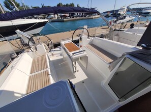 A boat deck with a steering wheel, control panel, and seating area.