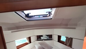 A compact, well-lit room with a bed, a skylight, and a view of the sea.