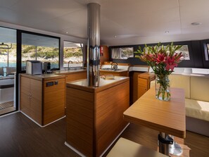 A modern kitchen with wooden cabinets, a stainless steel range hood, and a view of the sea. - Sun-Kissed Sailing Adventure in Sibenik, Croatia (Primošten)