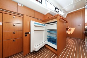 A compact kitchen with wooden cabinets, a built-in refrigerator, and a striped floor. - Sibenik Sun-soaked Sailing: A Luxurious Croatian Voyage (Pirovac)