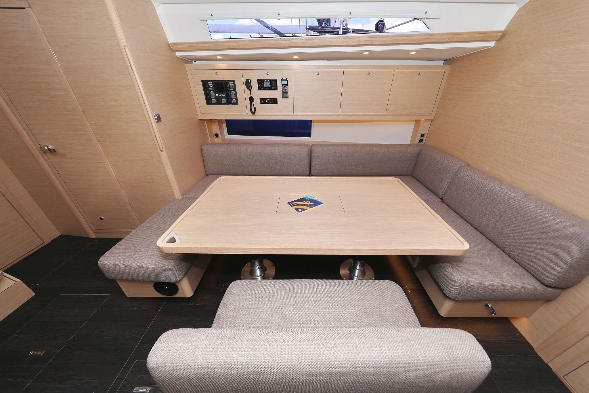 Een ruimtelijk interieur met een uitslaande tafel, zachte zitplaatsen en een bedieningspaneel erboven.