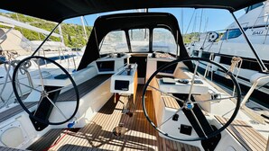 A boat's deck with a steering wheel, control panel, and a view of other boats in the marina. - Sun-Kissed Sailing Adventure in Sibenik, Croatia (Primošten)