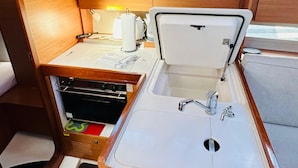 A compact kitchenette with a sink, stove, and storage cabinets. - Sun-Kissed Sailing Adventure in Sibenik, Croatia (Primošten)